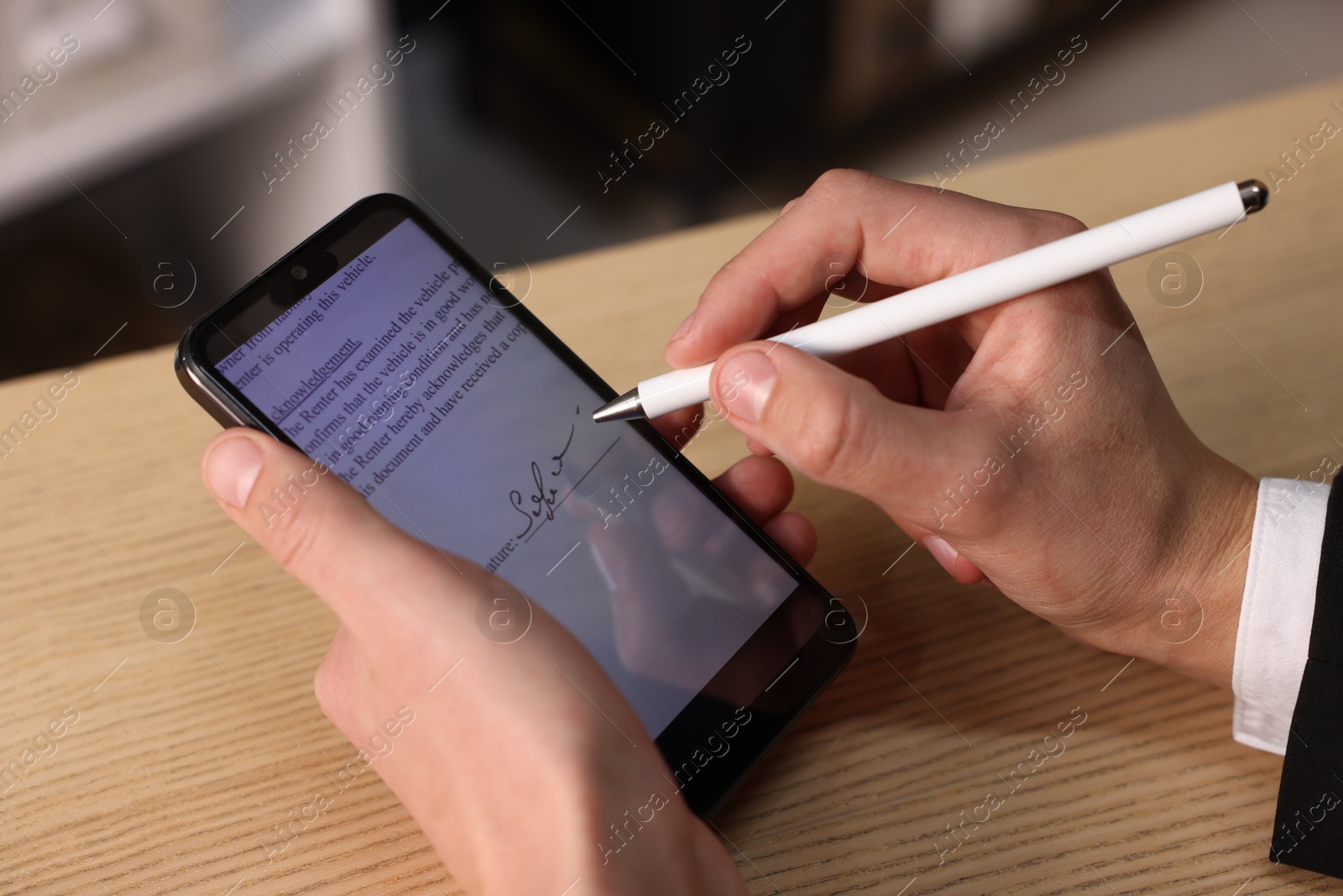 Photo of Electronic signature. Man using stylus and smartphone at wooden table, closeup