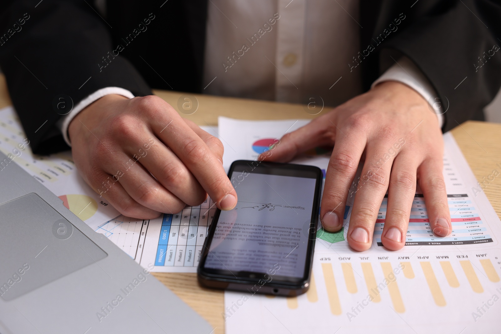 Photo of Electronic signature. Man using smartphone at table, closeup