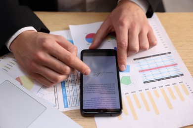 Photo of Electronic signature. Man using smartphone at wooden table, closeup