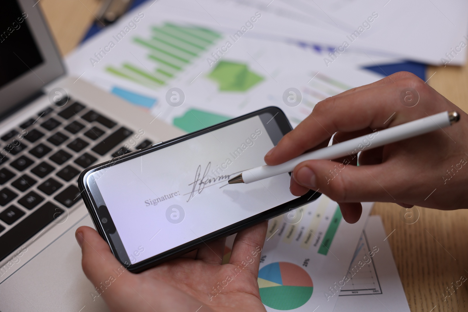 Photo of Electronic signature. Man using stylus and smartphone at wooden table, closeup