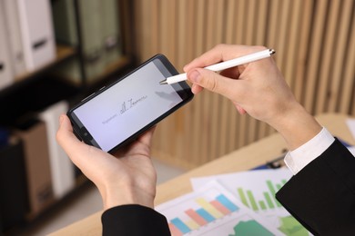 Photo of Electronic signature. Man using stylus and smartphone at table indoors, closeup