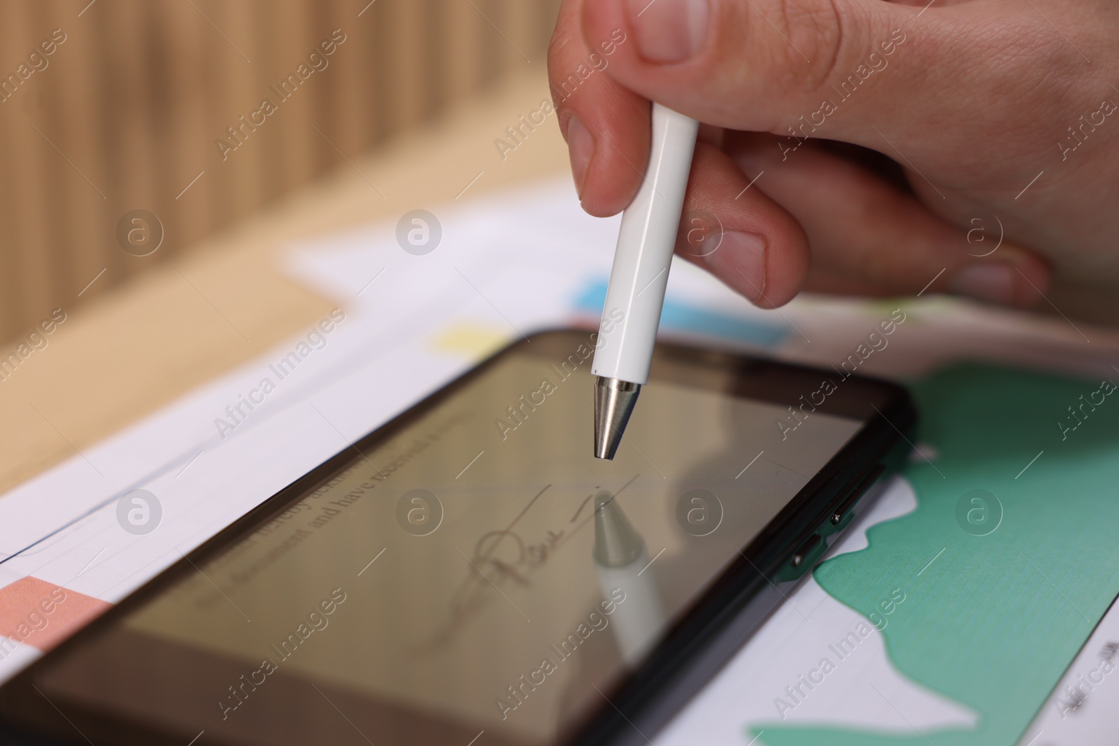 Photo of Electronic signature. Man using stylus and smartphone at table, closeup