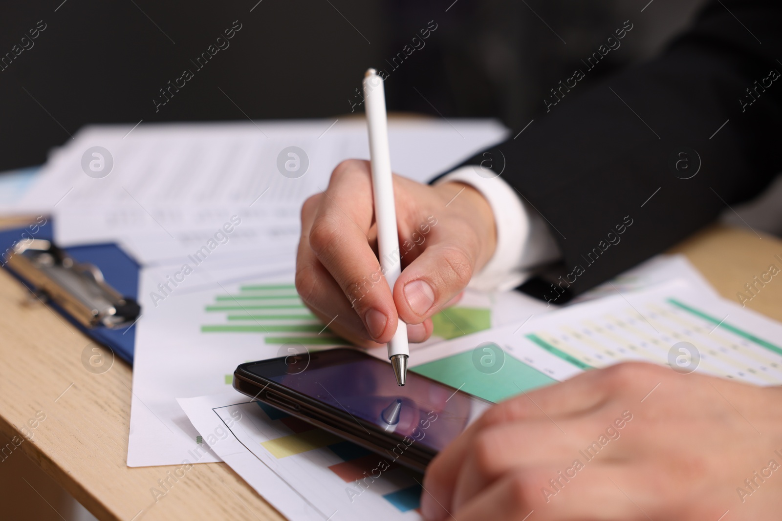 Photo of Electronic signature. Man using stylus and smartphone at wooden table, closeup