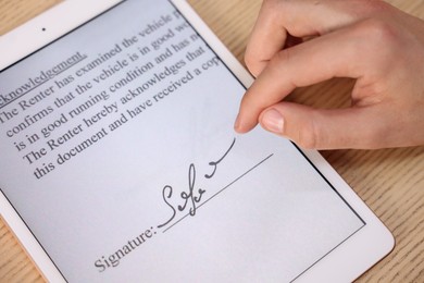 Photo of Electronic signature. Man using tablet at wooden table, above view