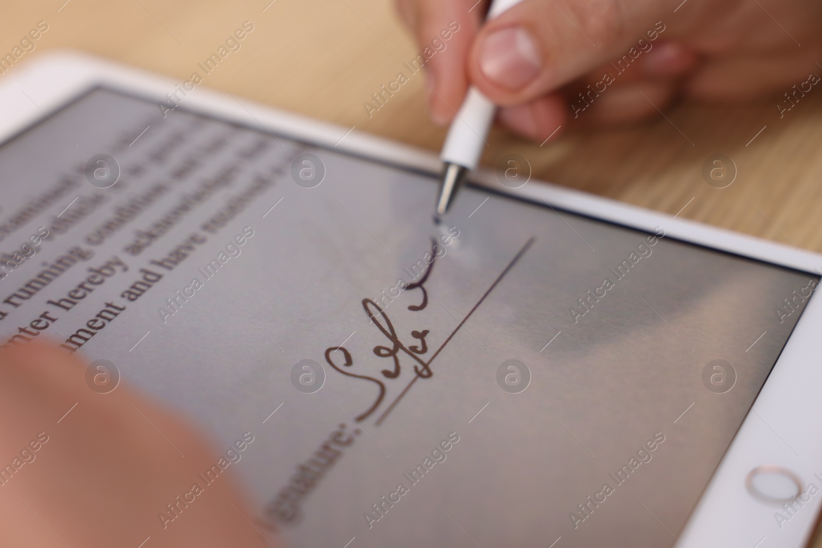 Photo of Electronic signature. Man using stylus and tablet at table, closeup