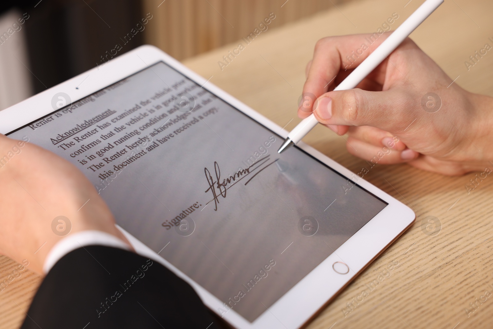 Photo of Electronic signature. Man using stylus and tablet at wooden table, closeup