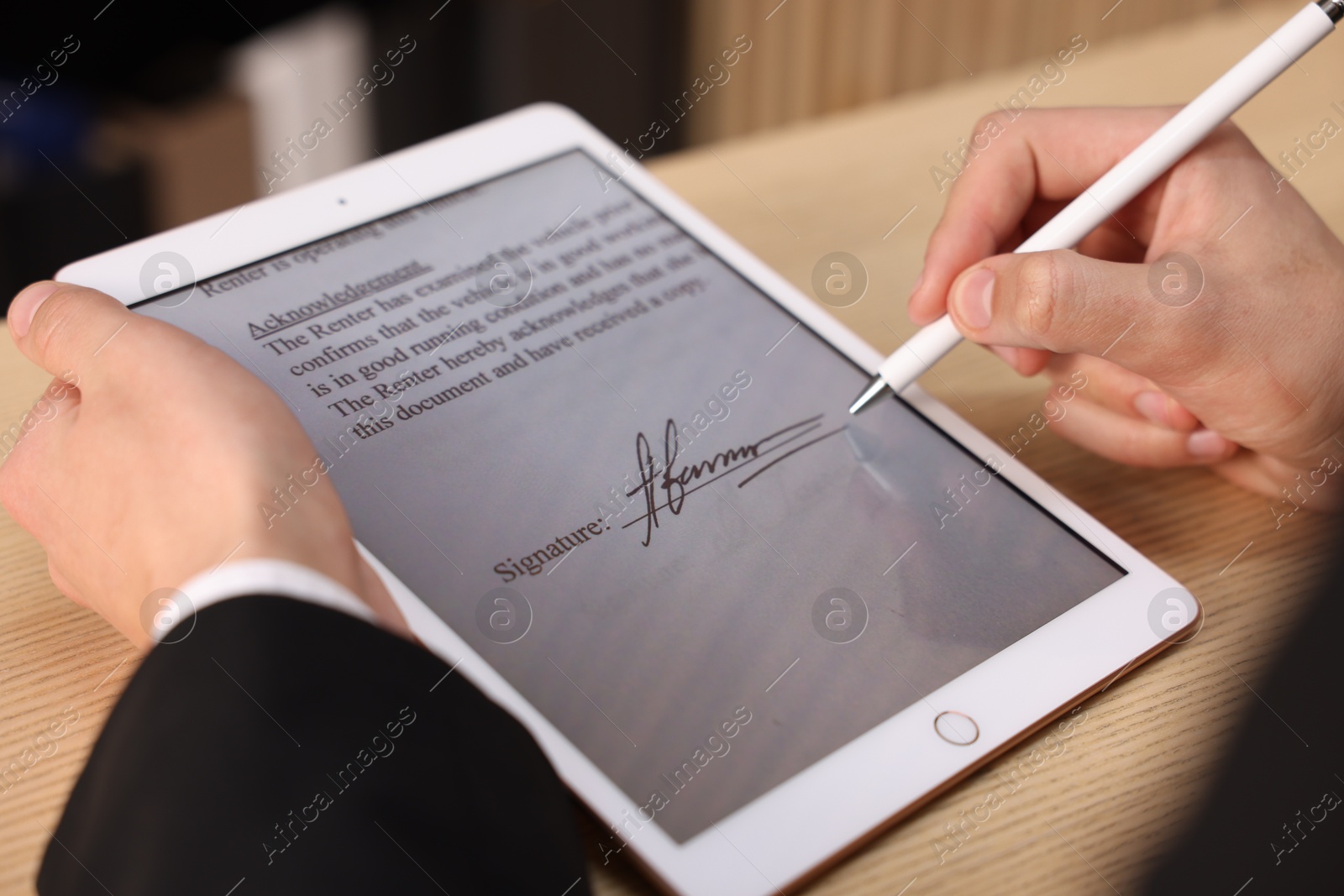 Photo of Electronic signature. Man using stylus and tablet at wooden table, closeup