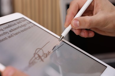 Photo of Electronic signature. Man using stylus and tablet indoors, closeup