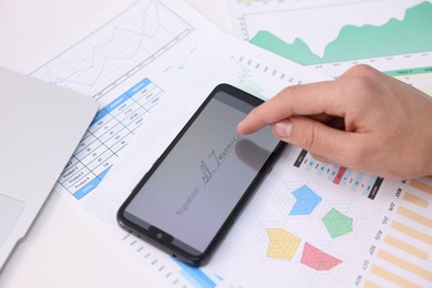 Photo of Electronic signature. Man using smartphone at table, above view