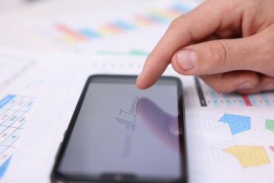 Photo of Electronic signature. Man using smartphone at table, closeup