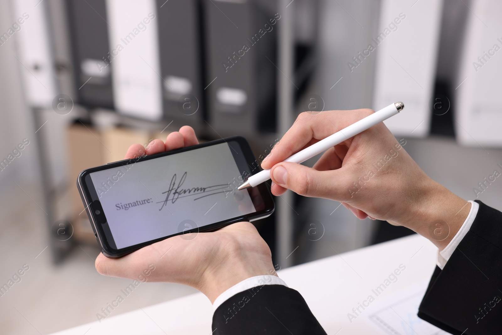 Photo of Electronic signature. Man using stylus and smartphone at white table indoors, closeup