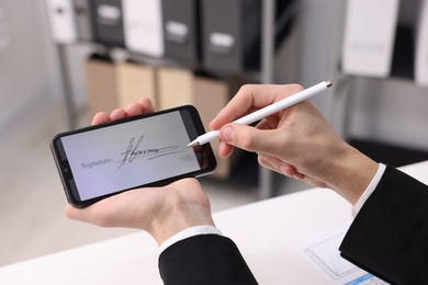 Photo of Electronic signature. Man using stylus and smartphone at white table indoors, closeup