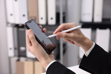 Photo of Electronic signature. Man using stylus and smartphone indoors, closeup