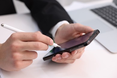 Photo of Electronic signature. Man using stylus and smartphone at white table, closeup