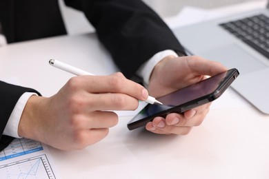 Photo of Electronic signature. Man using stylus and smartphone at white table, closeup