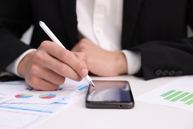 Photo of Electronic signature. Man using stylus and smartphone at white table, closeup