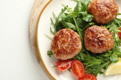 Photo of Delicious patties with greens and tomatoes on white table, top view. Space for text