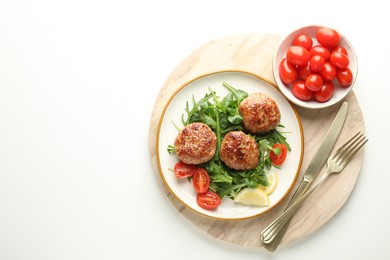 Photo of Delicious patties with greens, tomatoes and cutlery on white table, top view. Space for text