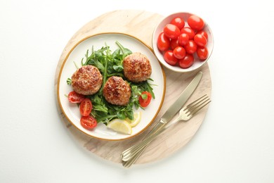 Photo of Delicious patties with greens, tomatoes and cutlery on white table, top view