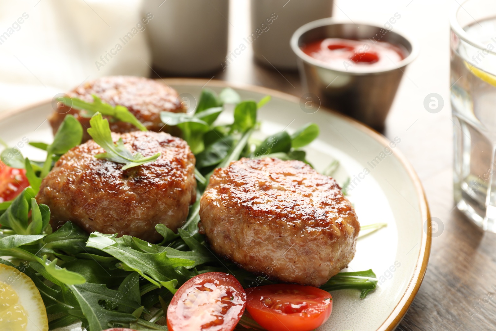 Photo of Delicious patties with greens, tomato, ketchup and drink on wooden table, closeup