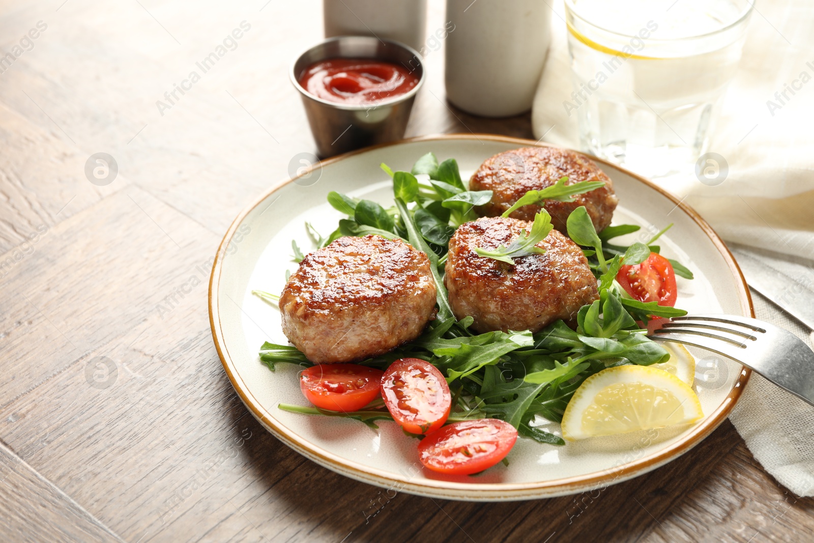 Photo of Delicious patties with greens, tomatoes, ketchup and drink on wooden table, closeup. Space for text