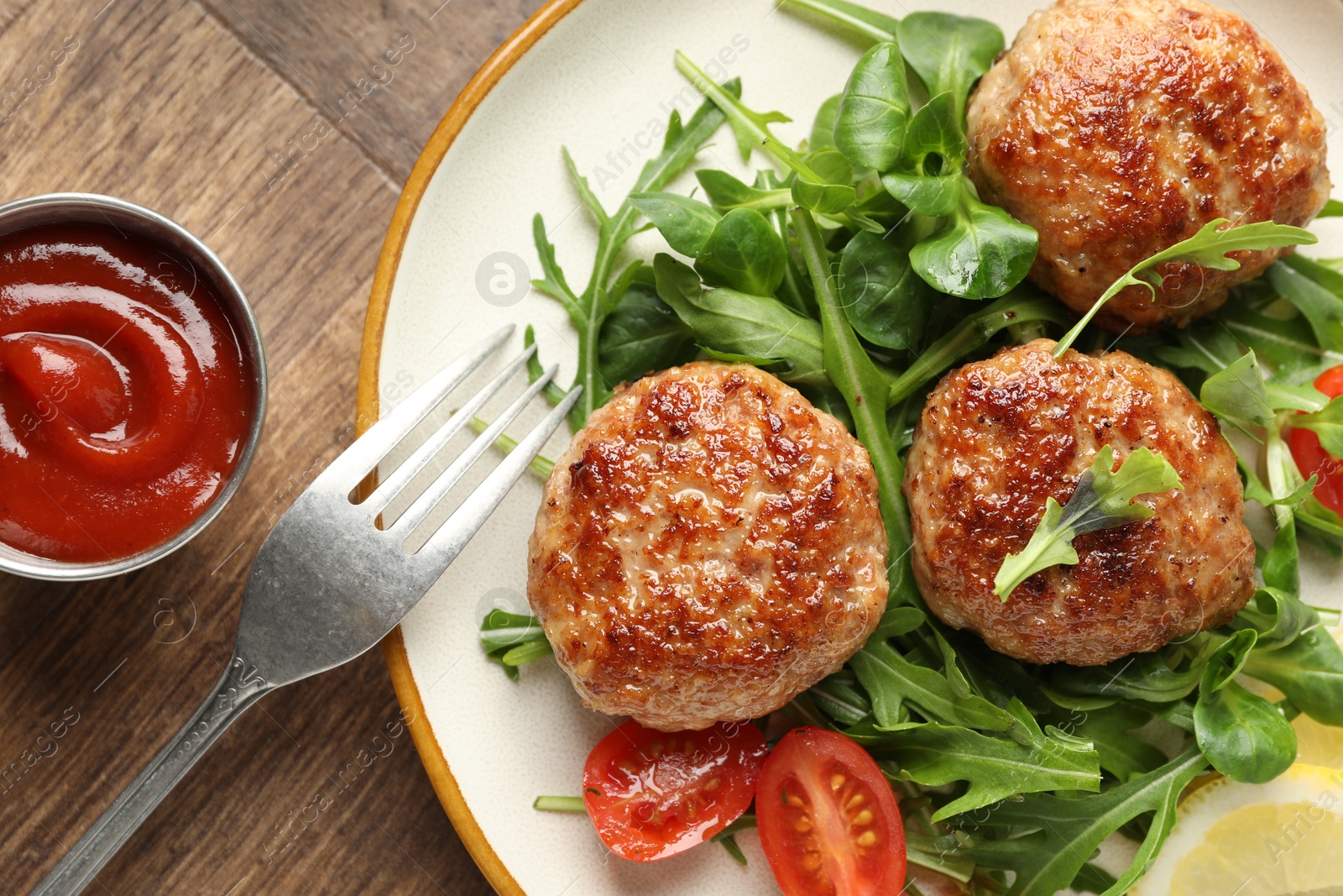 Photo of Delicious patties with greens, tomato and ketchup on wooden table, flat lay