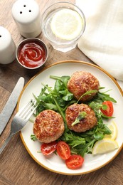 Photo of Delicious patties with greens, tomatoes, ketchup and drink on wooden table, flat lay