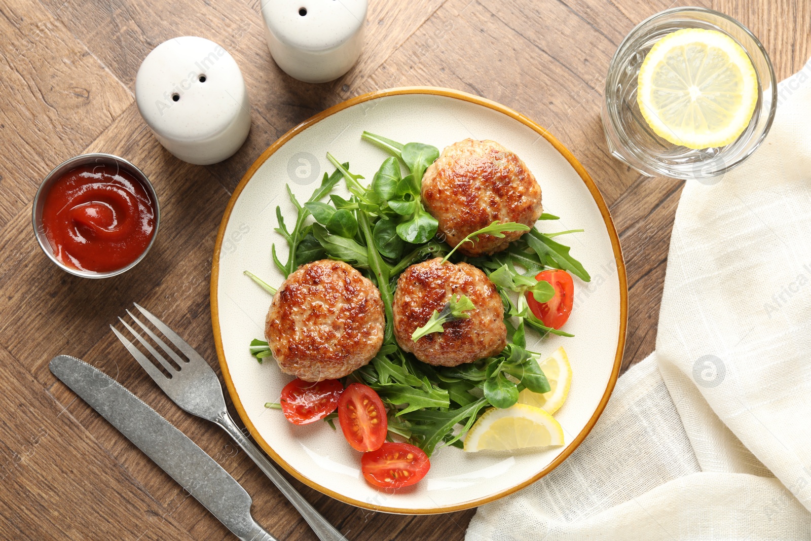 Photo of Delicious patties with greens, tomatoes, ketchup and drink on wooden table, flat lay