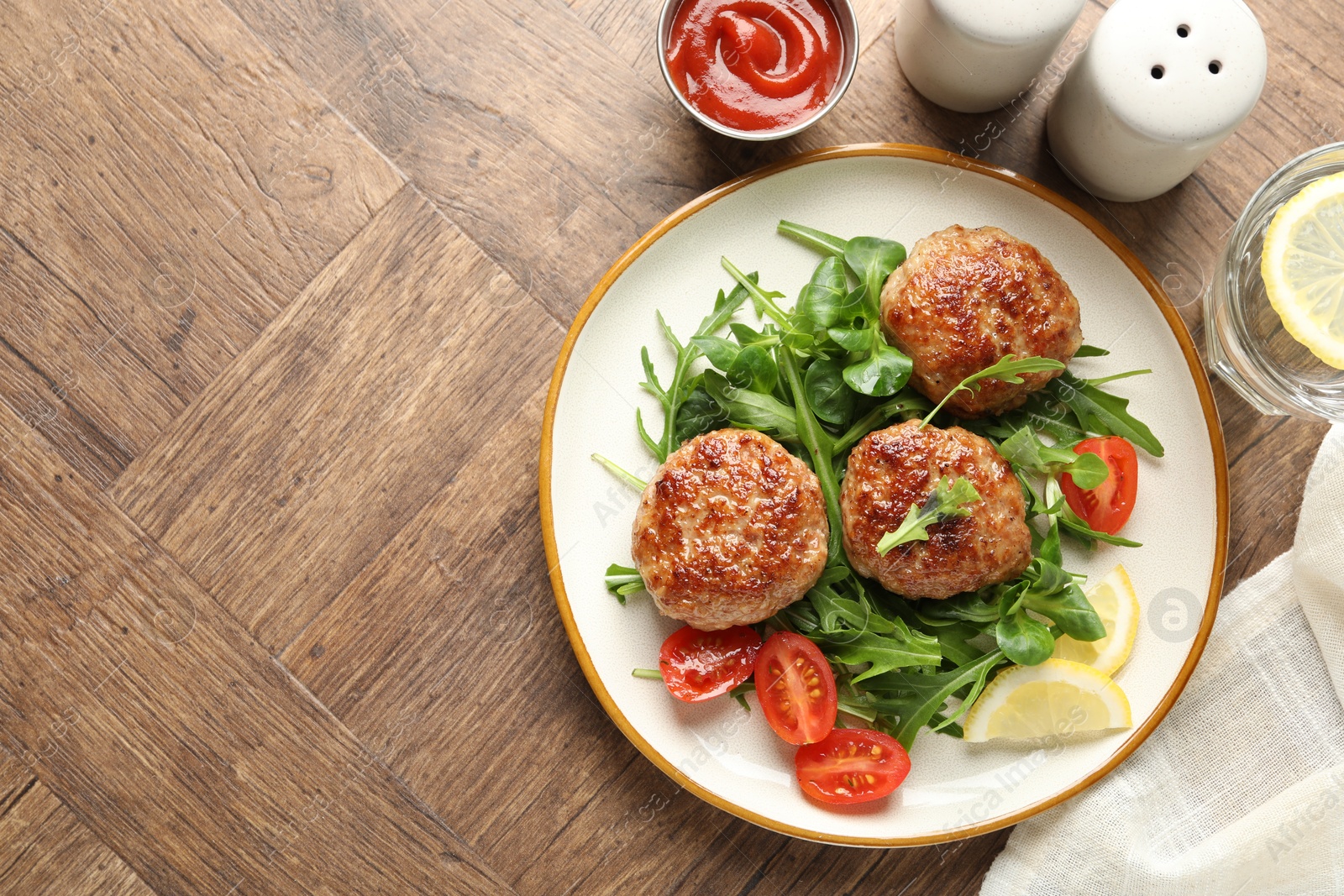 Photo of Delicious patties with greens, tomatoes, ketchup and drink on wooden table, flat lay. Space for text