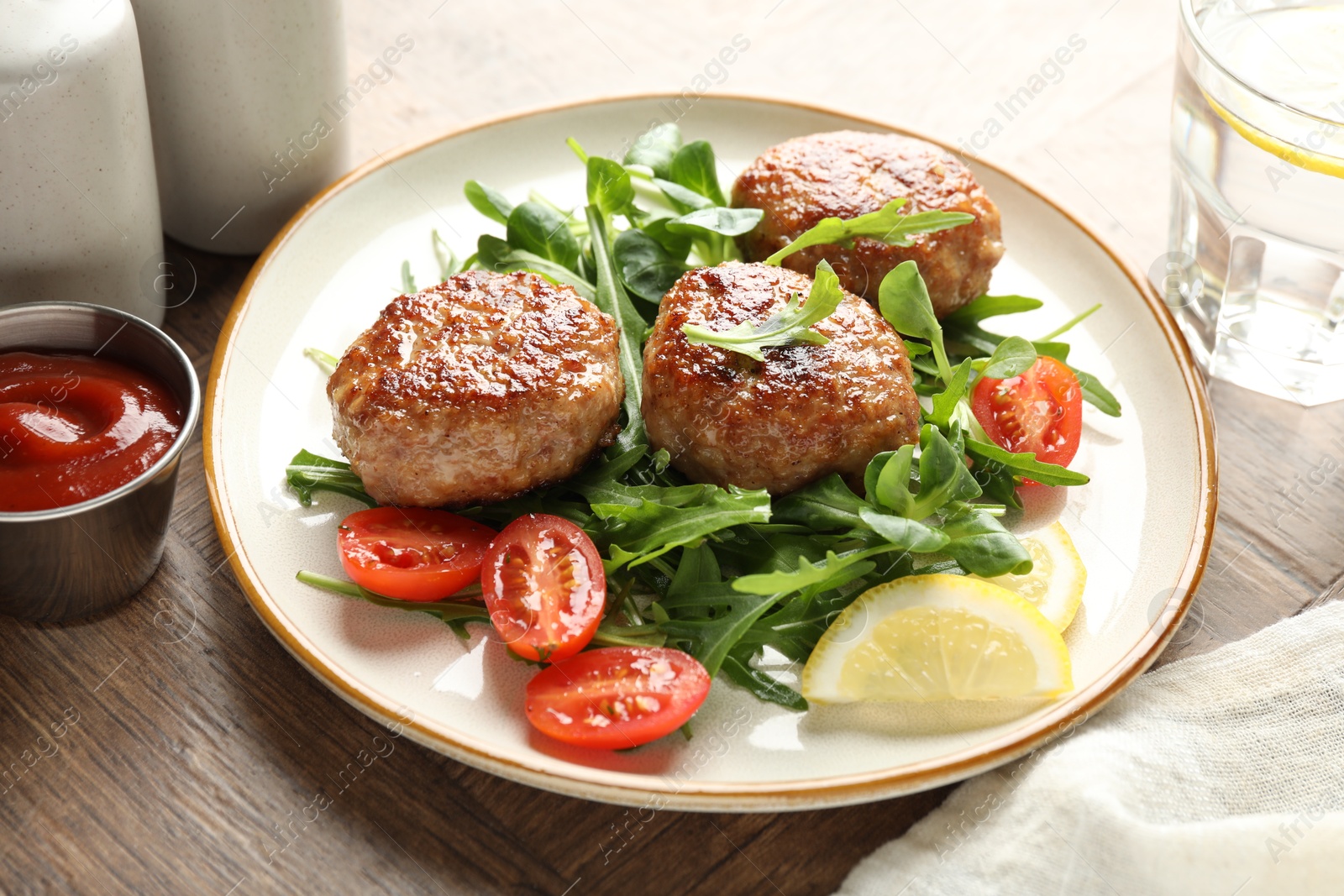 Photo of Delicious patties with greens, tomatoes, ketchup and drink on wooden table, closeup