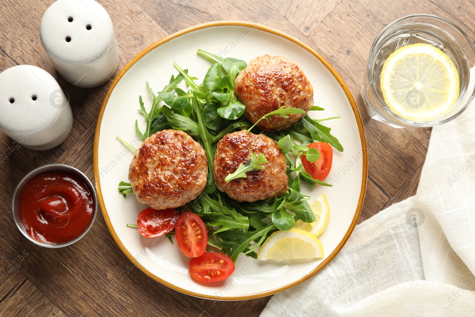 Photo of Delicious patties with greens, tomatoes, ketchup and drink on wooden table, flat lay