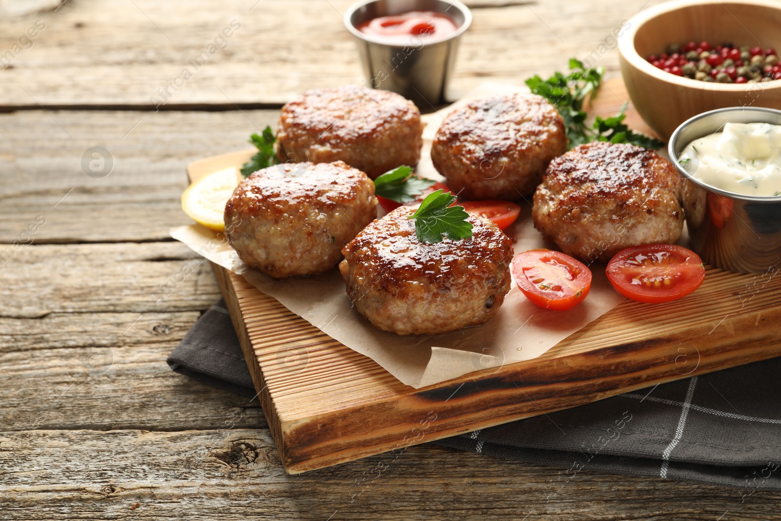 Photo of Delicious patties, spices, tomatoes and sauces on wooden table, closeup. Space for text