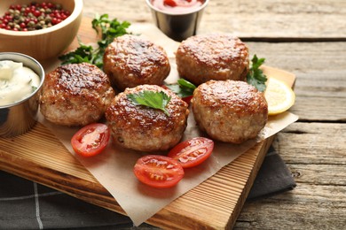 Photo of Delicious patties, spices, tomatoes and sauces on wooden table, closeup