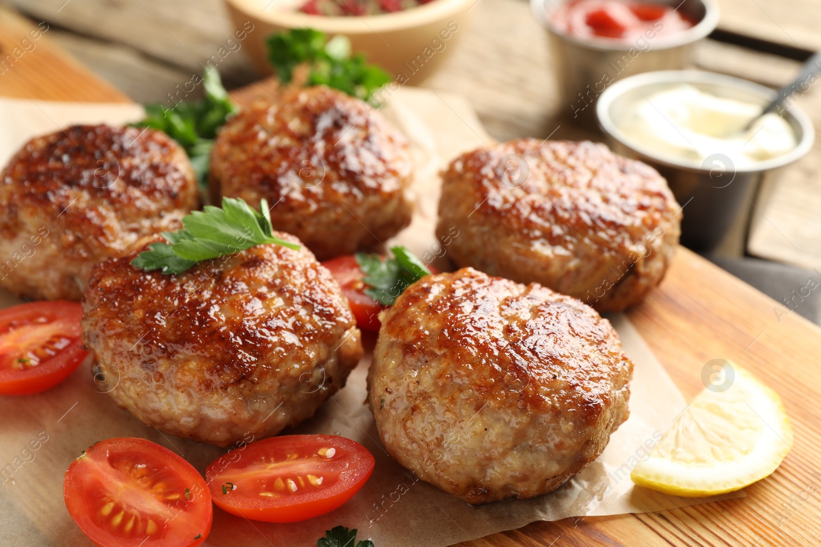 Photo of Delicious patties with parsley and tomatoes on table, closeup