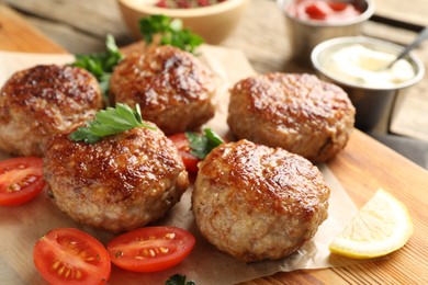 Photo of Delicious patties with parsley and tomatoes on table, closeup