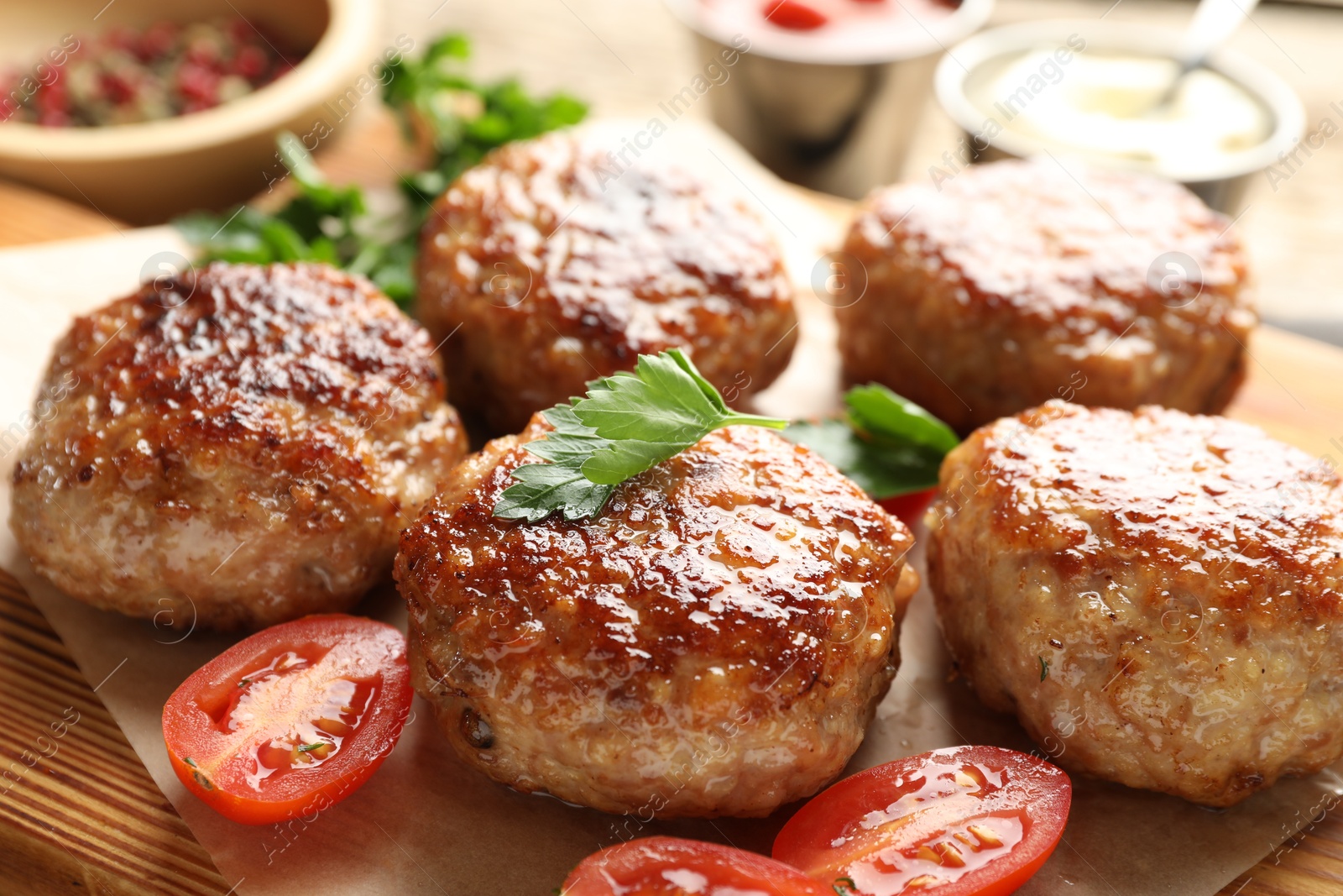 Photo of Delicious patties with parsley and tomatoes on table, closeup