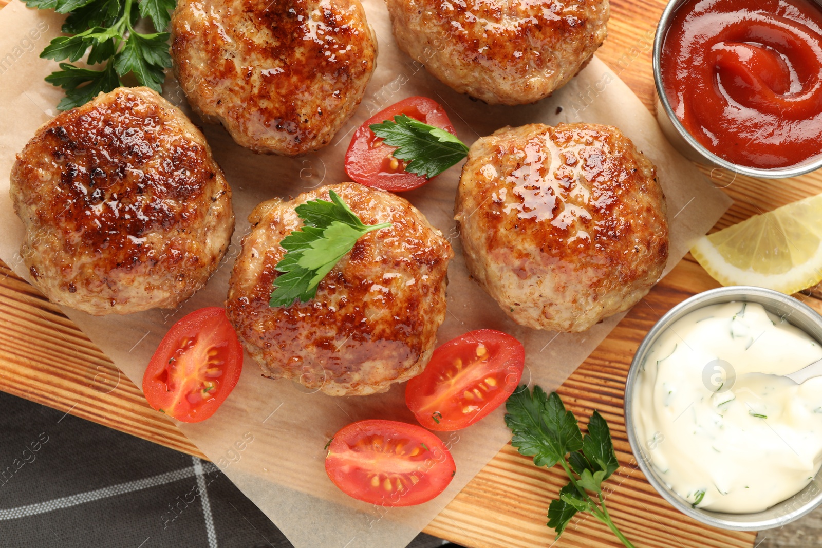 Photo of Delicious patties with parsley, tomatoes and sauces on table, top view