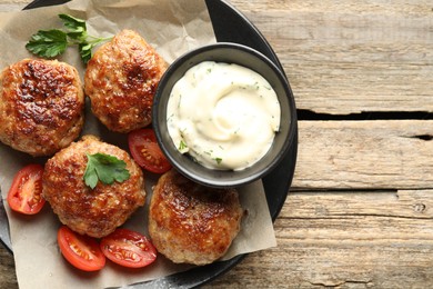 Photo of Delicious patties, parsley, tomatoes and sauce on wooden table, top view. Space for text