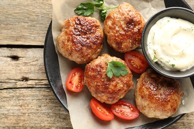 Photo of Delicious patties, parsley, tomatoes and sauce on wooden table, top view. Space for text