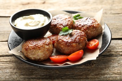 Photo of Delicious patties, parsley, tomatoes and sauce on wooden table, closeup