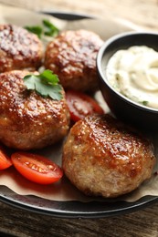 Photo of Delicious patties, parsley, tomatoes and sauce on wooden table, closeup