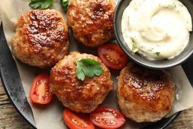 Photo of Delicious patties, parsley, tomatoes and sauce on wooden table, top view