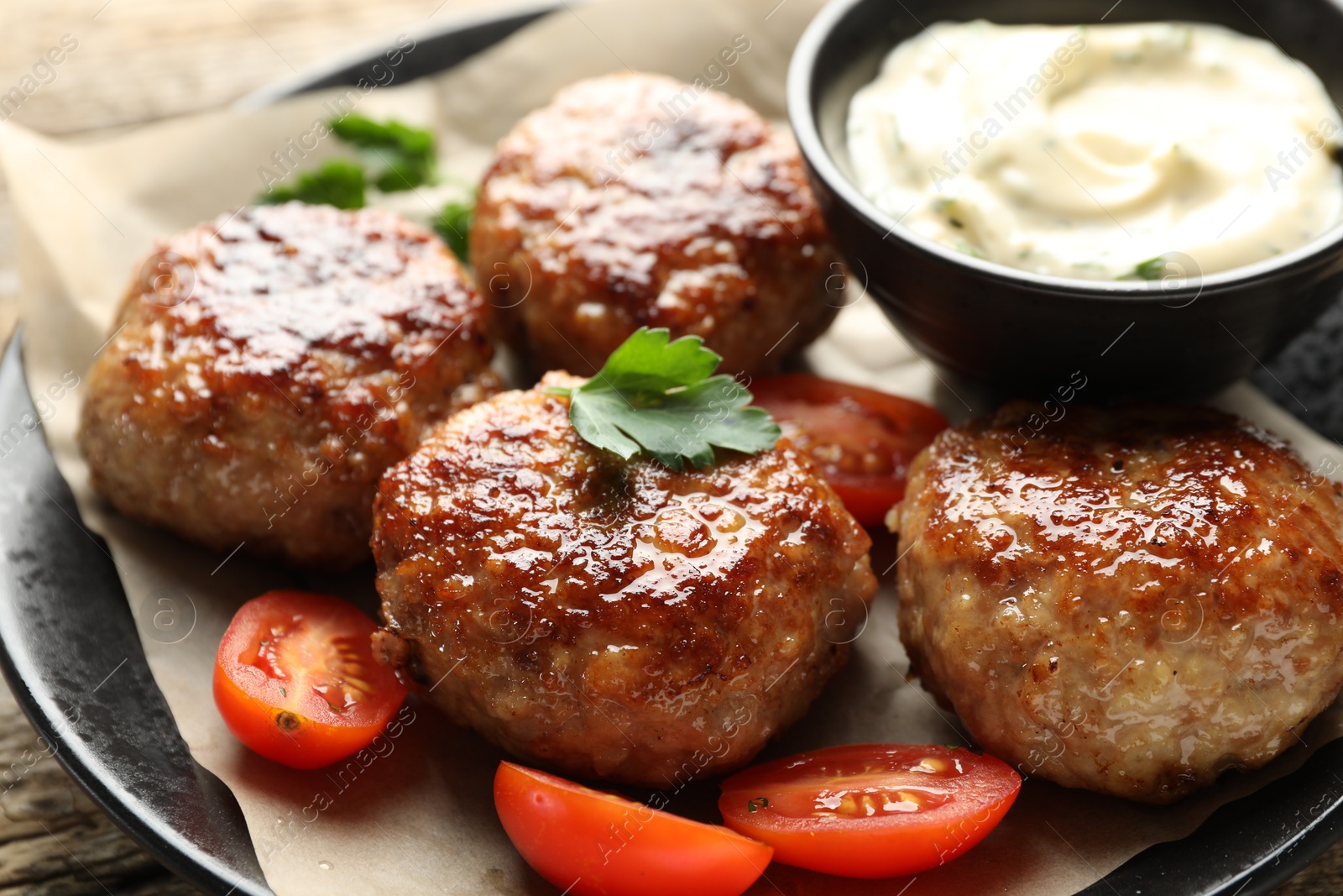 Photo of Delicious patties, parsley, tomatoes and sauce on table, closeup