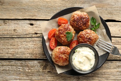 Photo of Delicious patties, parsley, tomatoes and sauce on wooden table, top view. Space for text