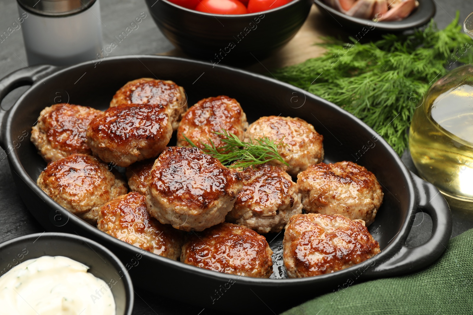 Photo of Delicious patties in baking dish and spices on table, closeup