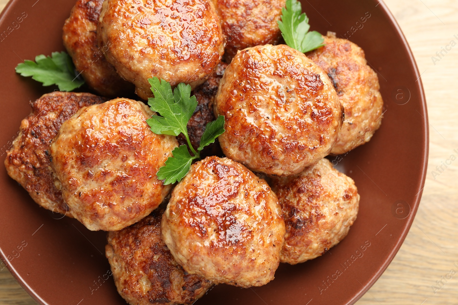 Photo of Delicious patties with parsley on wooden table, top view