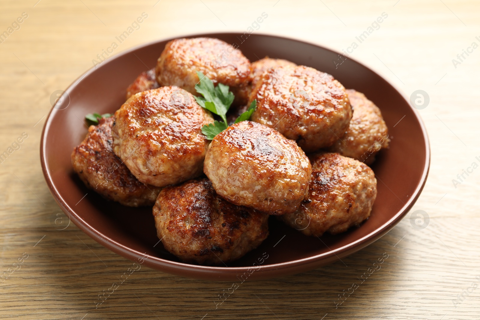 Photo of Delicious patties with parsley on wooden table, closeup