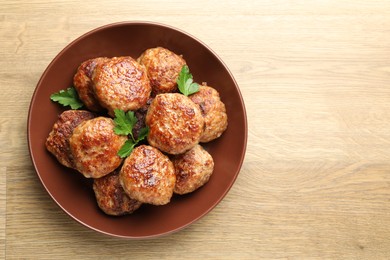 Photo of Delicious patties with parsley on wooden table, top view. Space for text