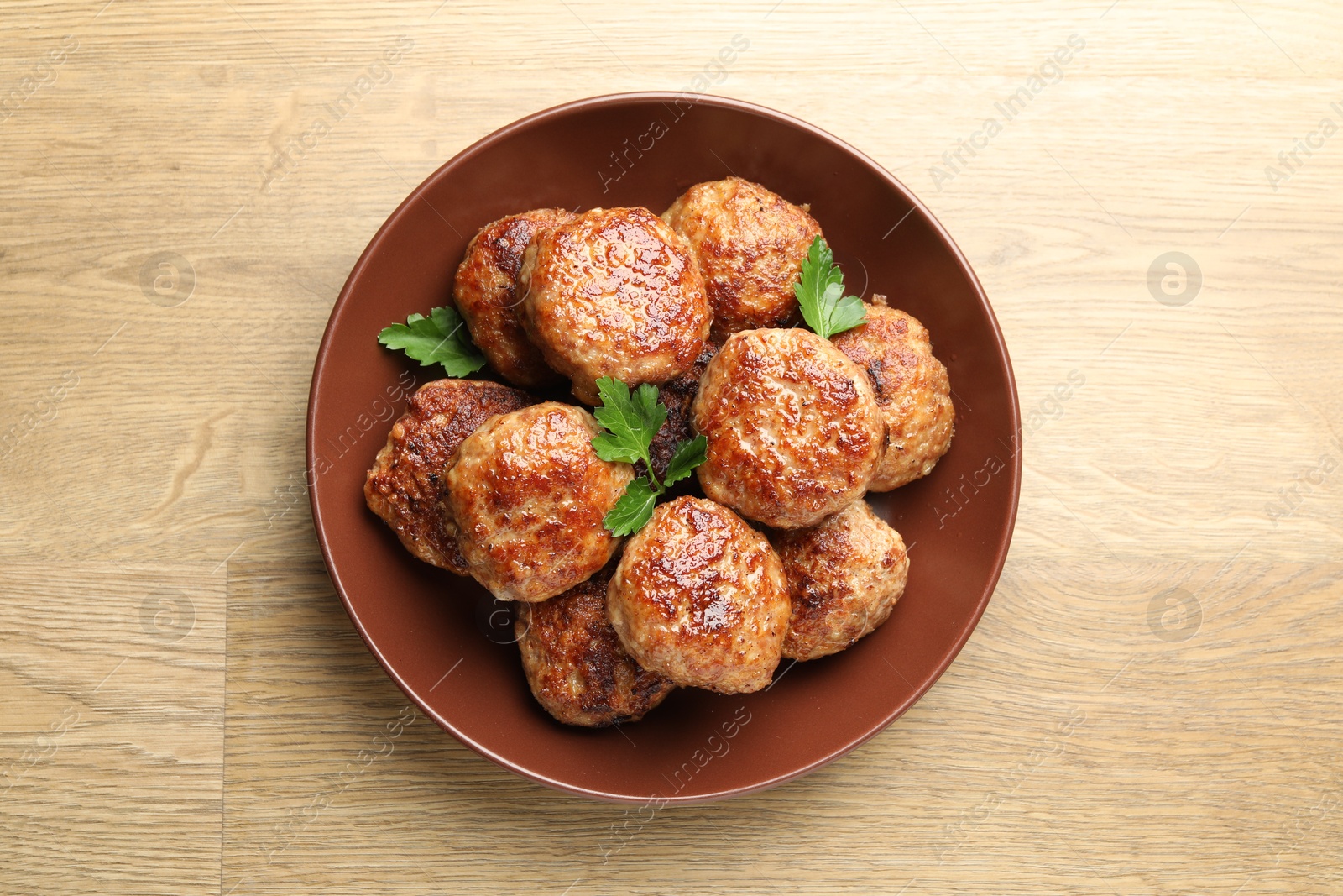 Photo of Delicious patties with parsley on wooden table, top view