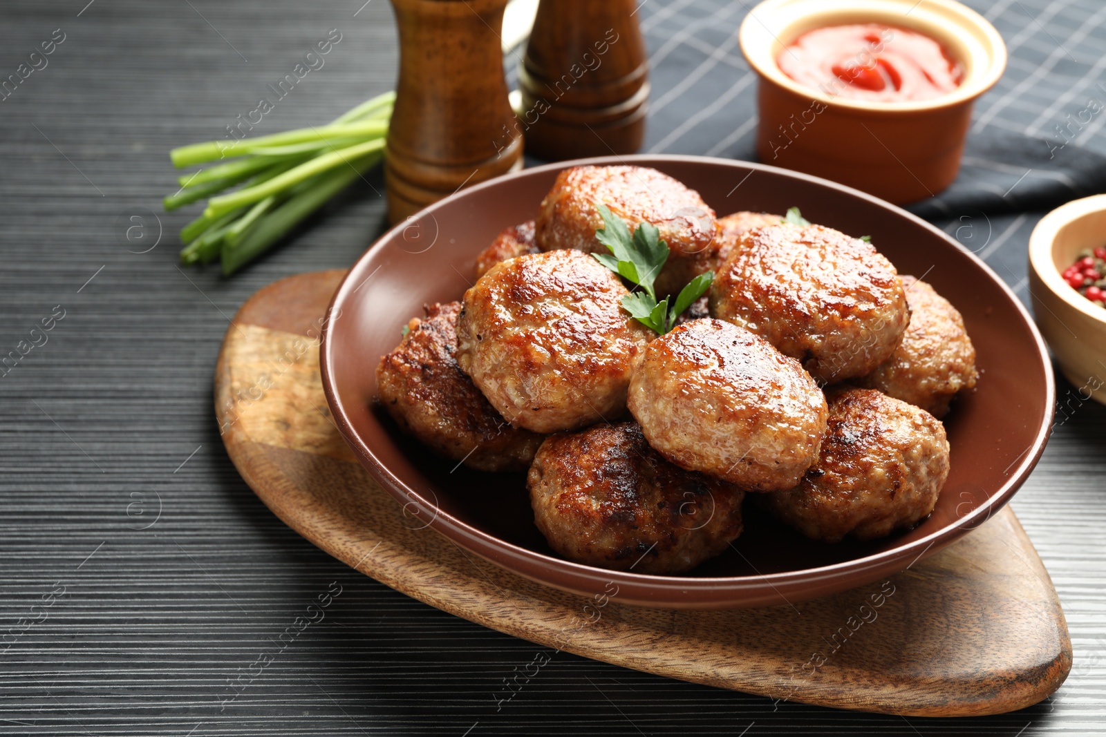 Photo of Delicious patties and spices on black textured table, closeup